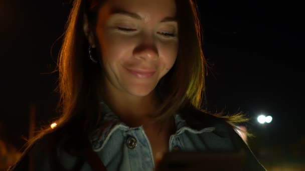 Νεαρή γυναίκα χρησιμοποιώντας το κινητό τηλέφωνο στο δρόμο τη νύχτα — Αρχείο Βίντεο