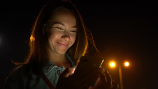 Mladá žena pomocí mobilního telefonu na ulici v noci — Stock video