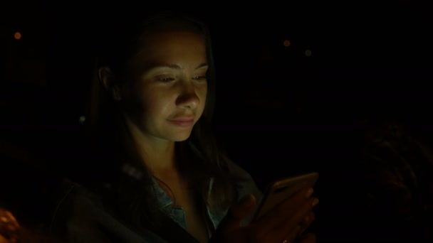 Young woman using mobile phone while sitting in a car at night — ストック動画