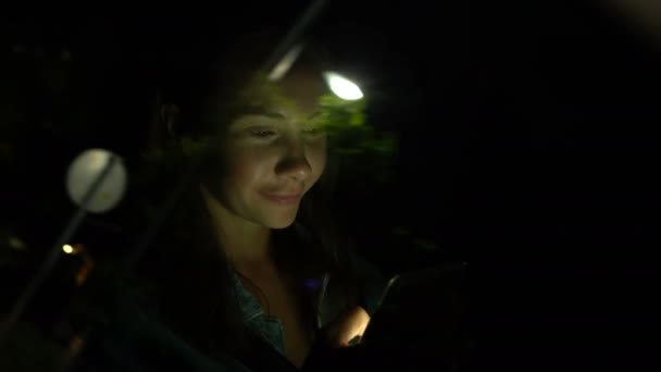 Jovem mulher usando telefone celular enquanto está sentado em um carro à noite — Vídeo de Stock