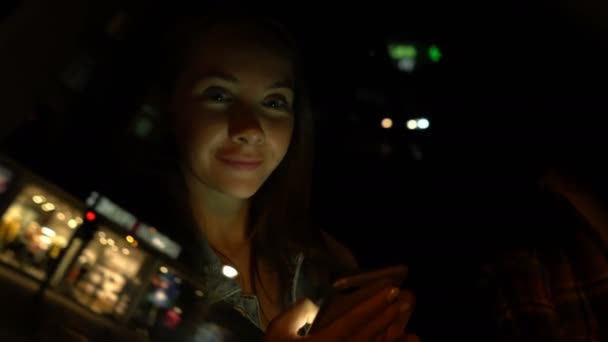 Ung kvinna som använder mobiltelefon när hon sitter i en bil på natten — Stockvideo
