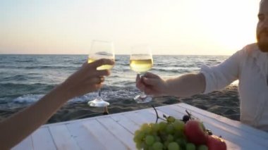 Deniz kenarında güzel bir çift, şarap ve meyveyle eğleniyorlar.