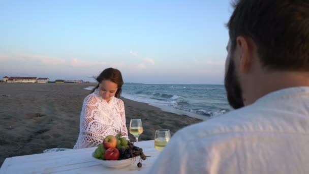 Aantrekkelijk paar aan zee met wijn en fruit genieten van elkaars gezelschap — Stockvideo