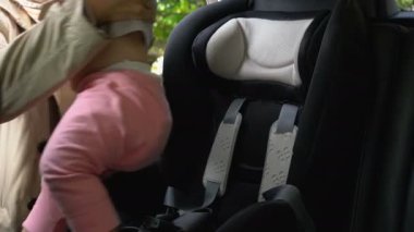 Anne bebeği bebek koltuğuna oturtur ve kemerini bağlar.