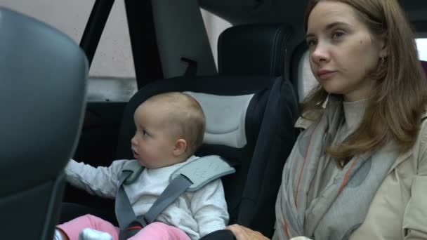 Mom and baby girl ride in the car in the back seat — Stock Video