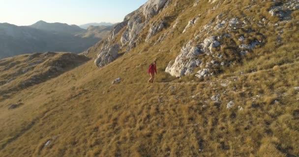 Tiro aéreo de um homem caminha nas montanhas — Vídeo de Stock