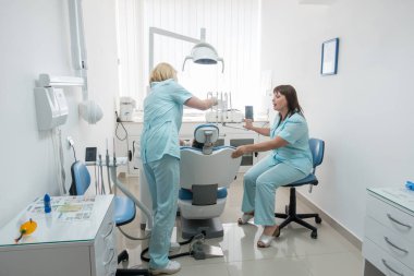 Küçük kız dişçi ofisinde oturuyor.