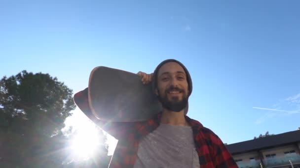 Portret van een lachende skateboarder met een baard die een skate op zijn schouder draagt — Stockvideo