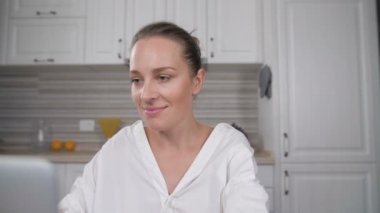 Mutfakta bilgisayarda çalışan genç bir kadının portresi.