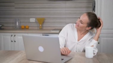 Mutfakta bilgisayarda çalışan genç bir kadının portresi.