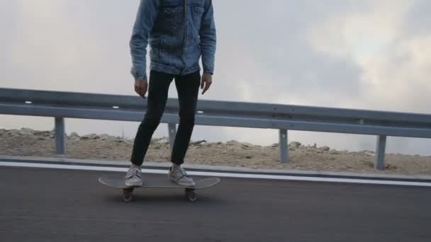 Jonge man met een baard paardrijden skateboard cruisen bergafwaarts op het platteland weg — Stockvideo