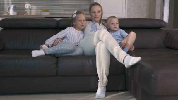 Mamma och två barn tittar på Tv sittande på soffan — Stockvideo