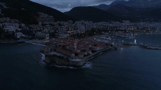 Antenn utsikt över kustnära gamla stan Budva med medeltida byggnader i skymningen — Stockvideo