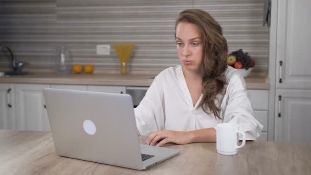 Droevige vrouw werken laptop computer in de keuken — Stockvideo