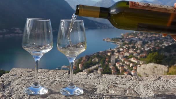 Weißwein wird vor dem Hintergrund der Bucht in ein Glas gegossen — Stockvideo