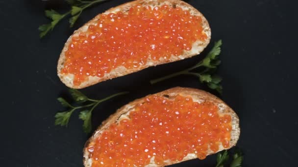 Sandwiches con caviar rojo sobre fondo de piedra oscura — Vídeo de stock