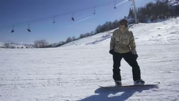 Сноубордист наслаждается горной прогулкой на горнолыжном курорте в солнечный день — стоковое видео