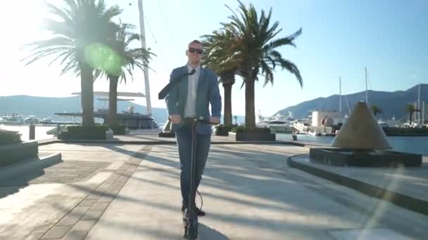 Knappe zakenman rijden op scooter gadget langs de jacht ligplaats. — Stockvideo