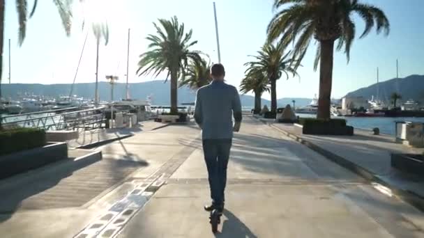 Handsome business guy driving on scooter gadget along the yacht mooring. — Stock Video