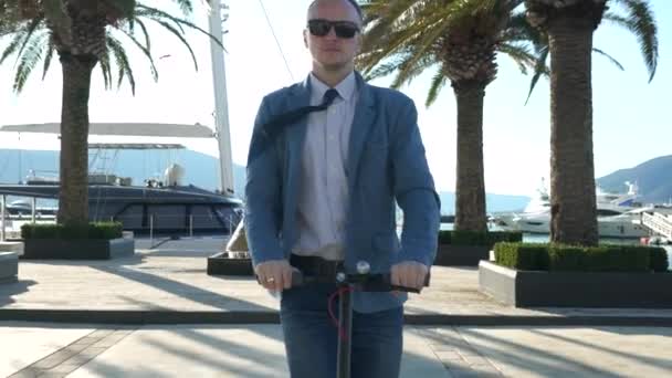 Knappe zakenman rijden op scooter gadget langs de jacht ligplaats. — Stockvideo