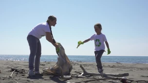 Семья забирает мусор с пляжа в мешках для мусора — стоковое видео