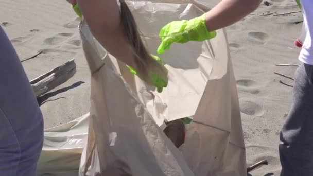 가족들 이 해변에서 쓰레기를 쓰레기 봉투에 담아 가지고 간다 — 비디오