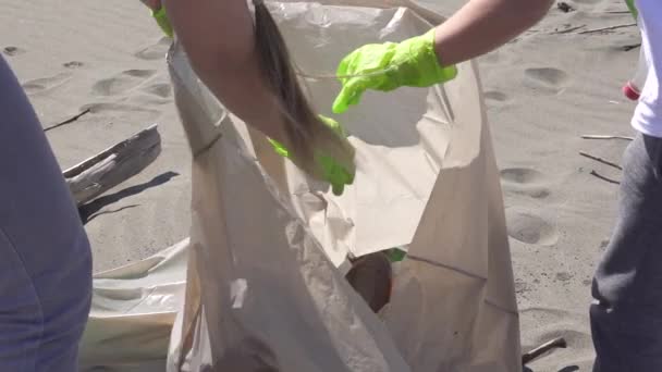 Famiglia raccoglie rifiuti dalla spiaggia in sacchi della spazzatura — Video Stock