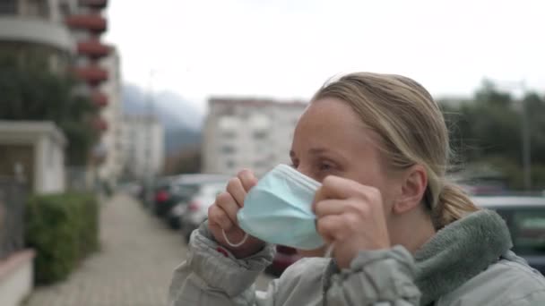 Женщина надевает хирургическую маску для профилактики коронного вируса. — стоковое видео