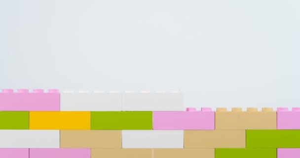 Ladrillos de colores haciendo pared sobre fondo blanco — Vídeo de stock