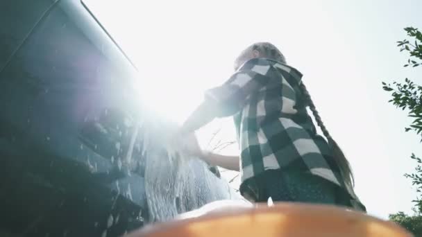 Åtta år gammal flicka tvättar en bil med tvål och en svamp — Stockvideo