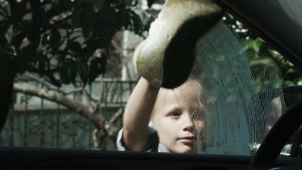 Menina de oito anos lava um carro com sabão e uma esponja — Vídeo de Stock
