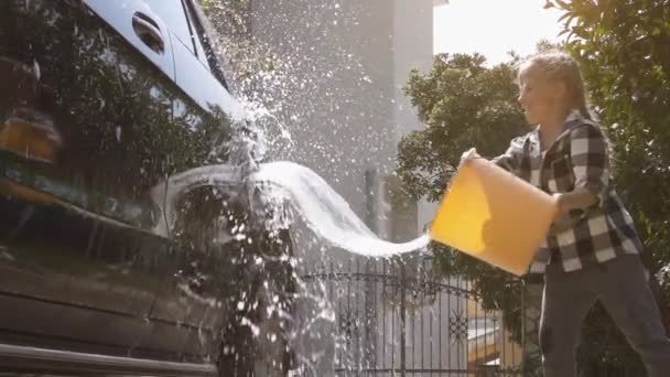 Chica salpicando agua de un cubo en un coche — Vídeos de Stock