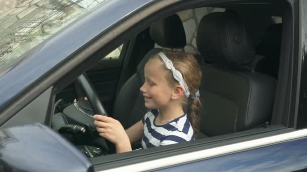 Niña de ocho años sentada al volante de un coche — Vídeos de Stock