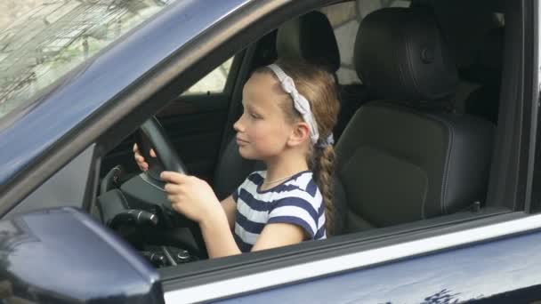 Acht jaar oud meisje zit achter het stuur van een auto — Stockvideo