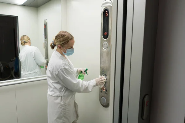 Donna che utilizza salviette umidificate e alcool disinfettante spray per pulire un pannello di controllo pulsante ascensore. Disinfezione, pulizia e assistenza sanitaria, Anti Coronavirus COVID-19 — Foto Stock