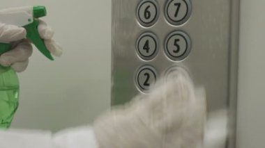 Asansör düğmesi kontrol panelini temizlemek için ıslak mendil ve alkol dezenfektanı kullanan bir kadın. Dezenfeksiyon, temizlik ve sağlık hizmetleri, Anti Coronavirüs COVID-19