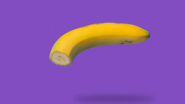 Банан з'являється і зникає на фіолетовому фоні — стокове відео