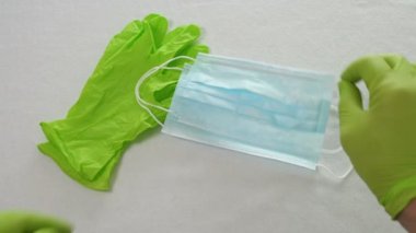 Doktor ellerinde yeşil tıbbi eldivenlerle korunan solunum maskesi olduğunu gösteriyor. Pandemik sigorta hava hastalıkları, SARS, grippe, coronavirus. İnsan için tıbbi maskeler.