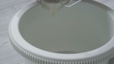 Karıştırıcıyla yumurta beyazı çırpıyor.