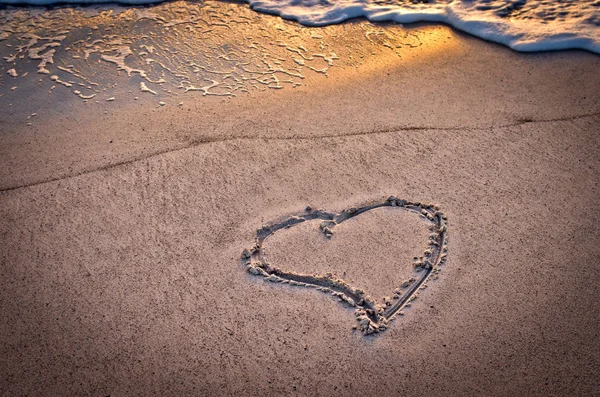 Un cœur sur la plage au coucher du soleil — Photo