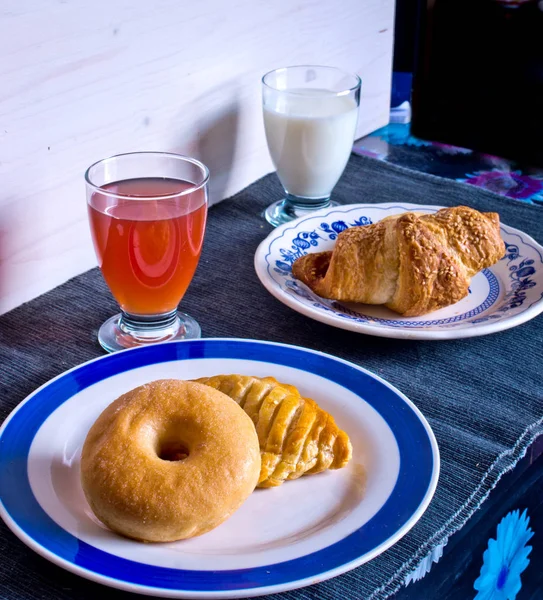 breakfast with donuts, salty croissant, fruit juice and milk