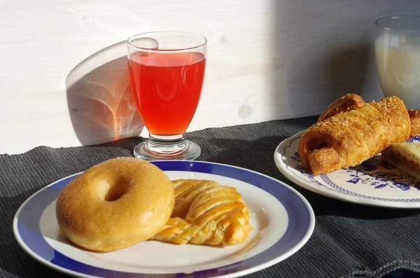Breakfast with donuts, salty croissant, fruit juice and milk — Stock Photo, Image