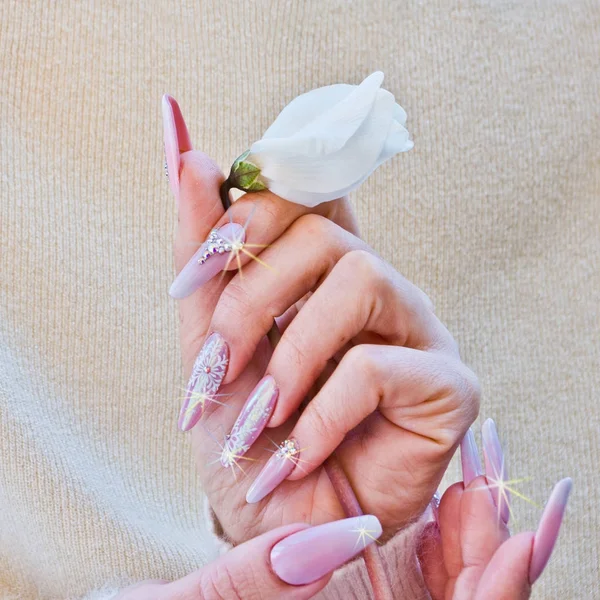Weiße Blume angeboten mit Händen mit Nägeln mit Weihnachtsdekoration — Stockfoto