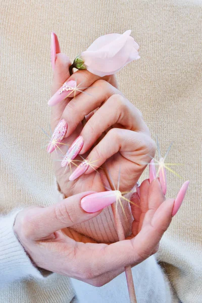 Las manos con las uñas adornadas con el color rosado y blanco aprietan w — Foto de Stock