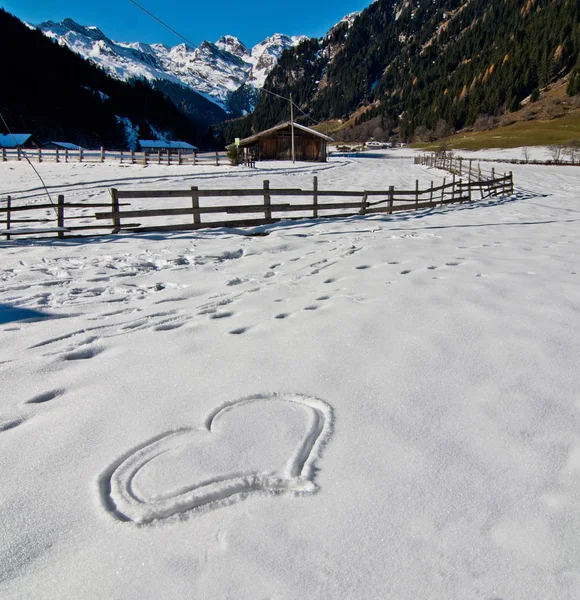Heart etched in the snow with mountains in the background Stock Photo