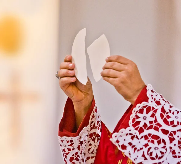 Mãos do sacerdote levantar o corpo de Cristo — Fotografia de Stock