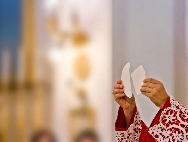 Mãos do sacerdote levantar o corpo de Cristo — Fotografia de Stock