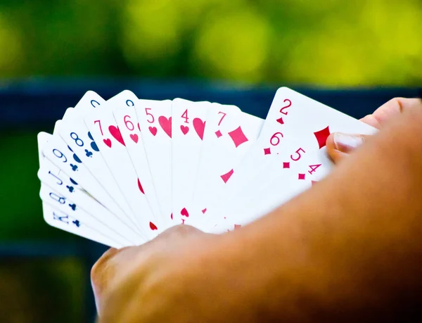 Person playing cards with green background — Stock Photo, Image
