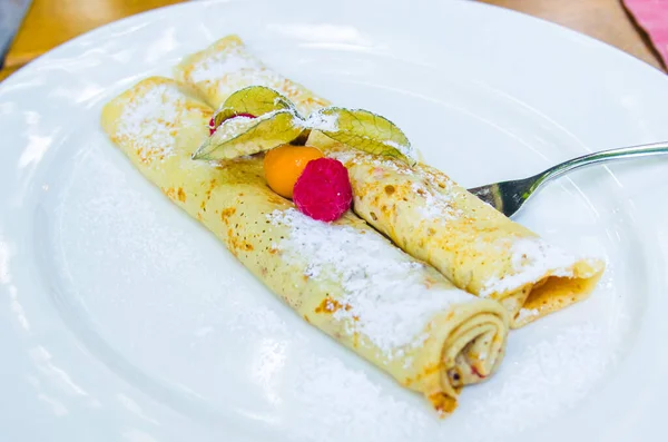crepes filled with chocolate and berries with wild strawberries and cape gooseberries
