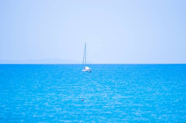 Mavi denizde ve mavi gökyüzü benekli adanın altında en üstteki teknede yol gösterici.